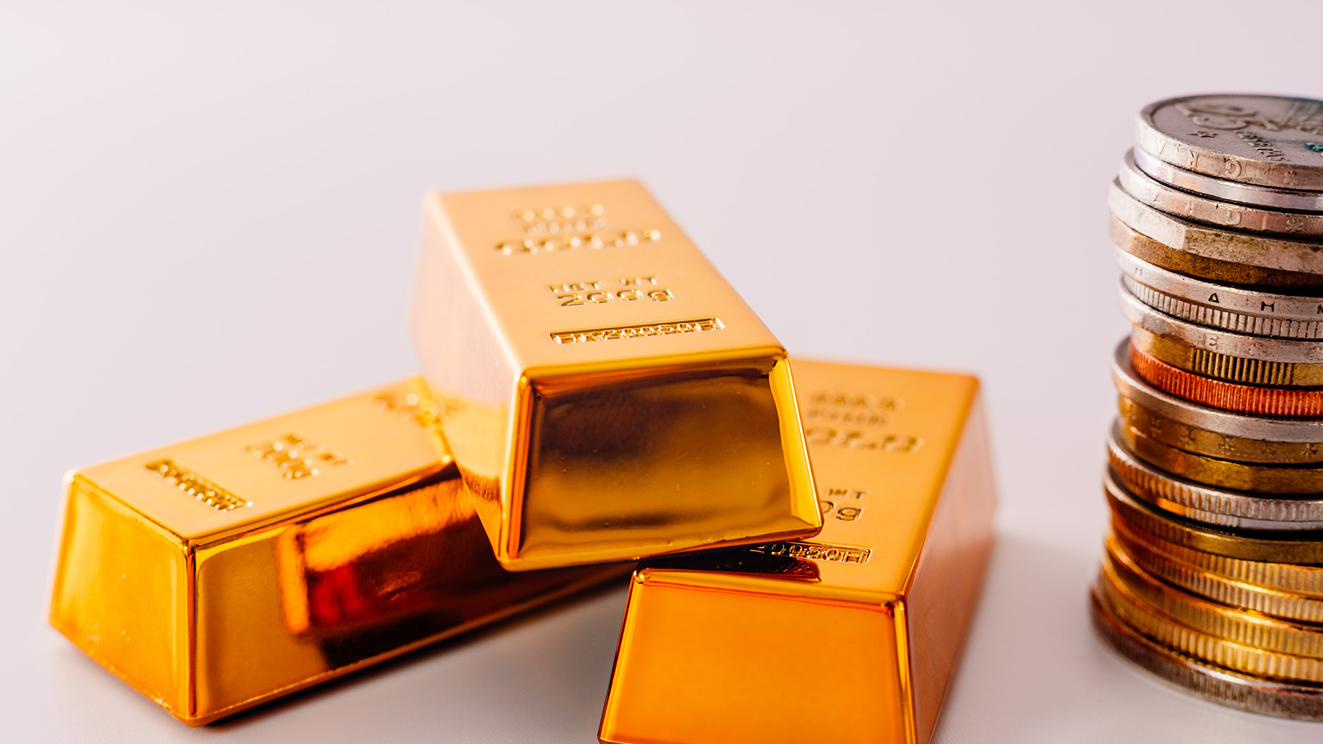 3 gold bars and currency coins amid Gold Remains being the First Safe Haven